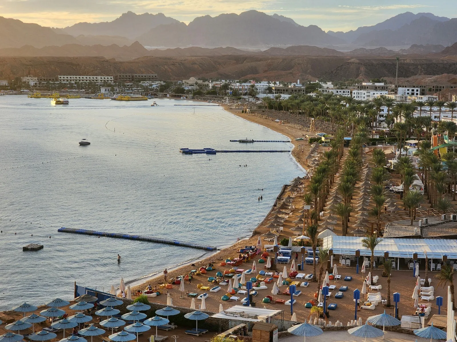 Sichelförmige Bucht von Sharm el-Sheikh mit Sonnenschirmen vor der Kulisse der Sinai-Berge