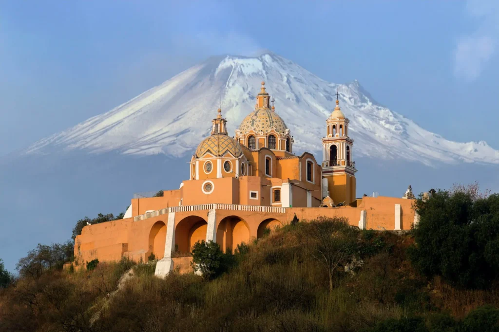 Kirche von Cholula vor dem schneebedeckten Vulkan Popocatépetl in Mexiko