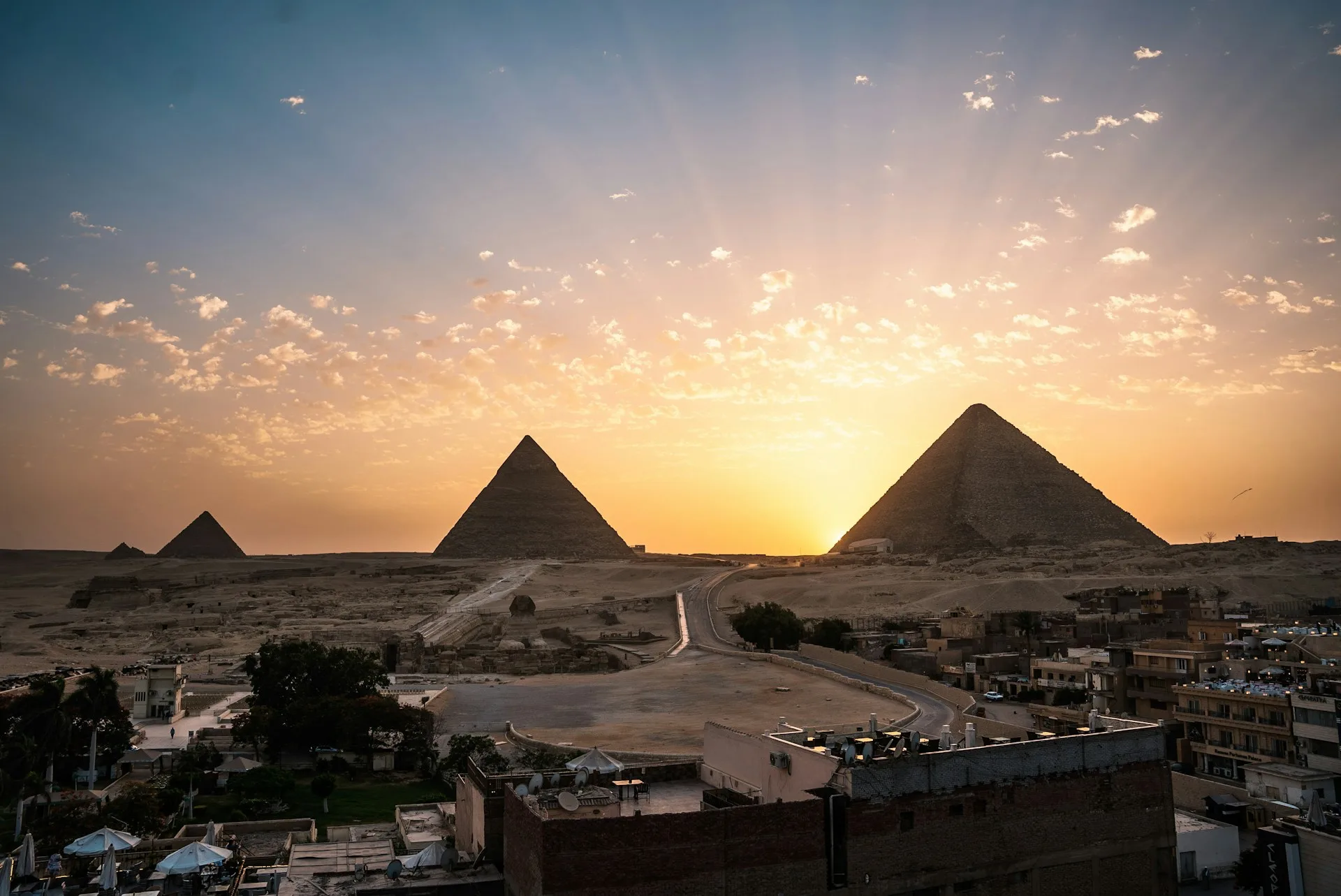 Pyramiden von Gizeh in Aegypten bei Sonnenuntergang mit oranger Wueste