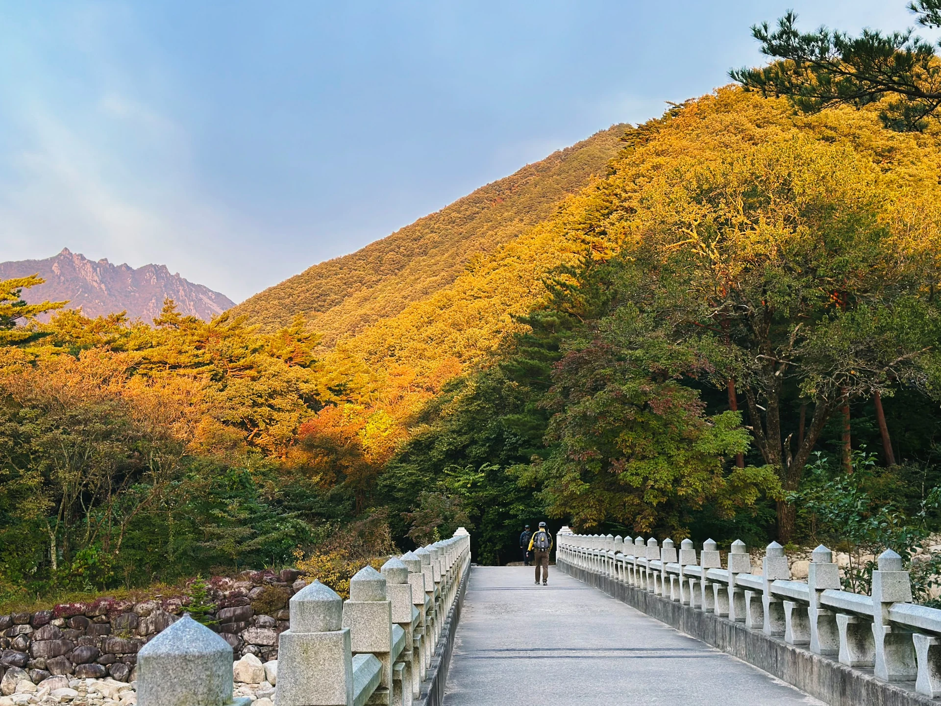 Brücke über einen Fluss vor bewaldeten Bergen in Südkorea im Herbst