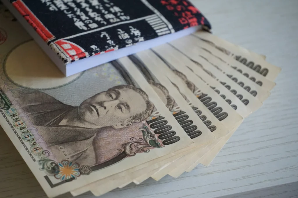 Aufgefächerte 10.000-Yen-Scheine neben einem Buch mit japanischer Schrift